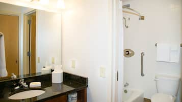 A bathroom with a sink, mirror, towel rack, and shower with a grab bar.