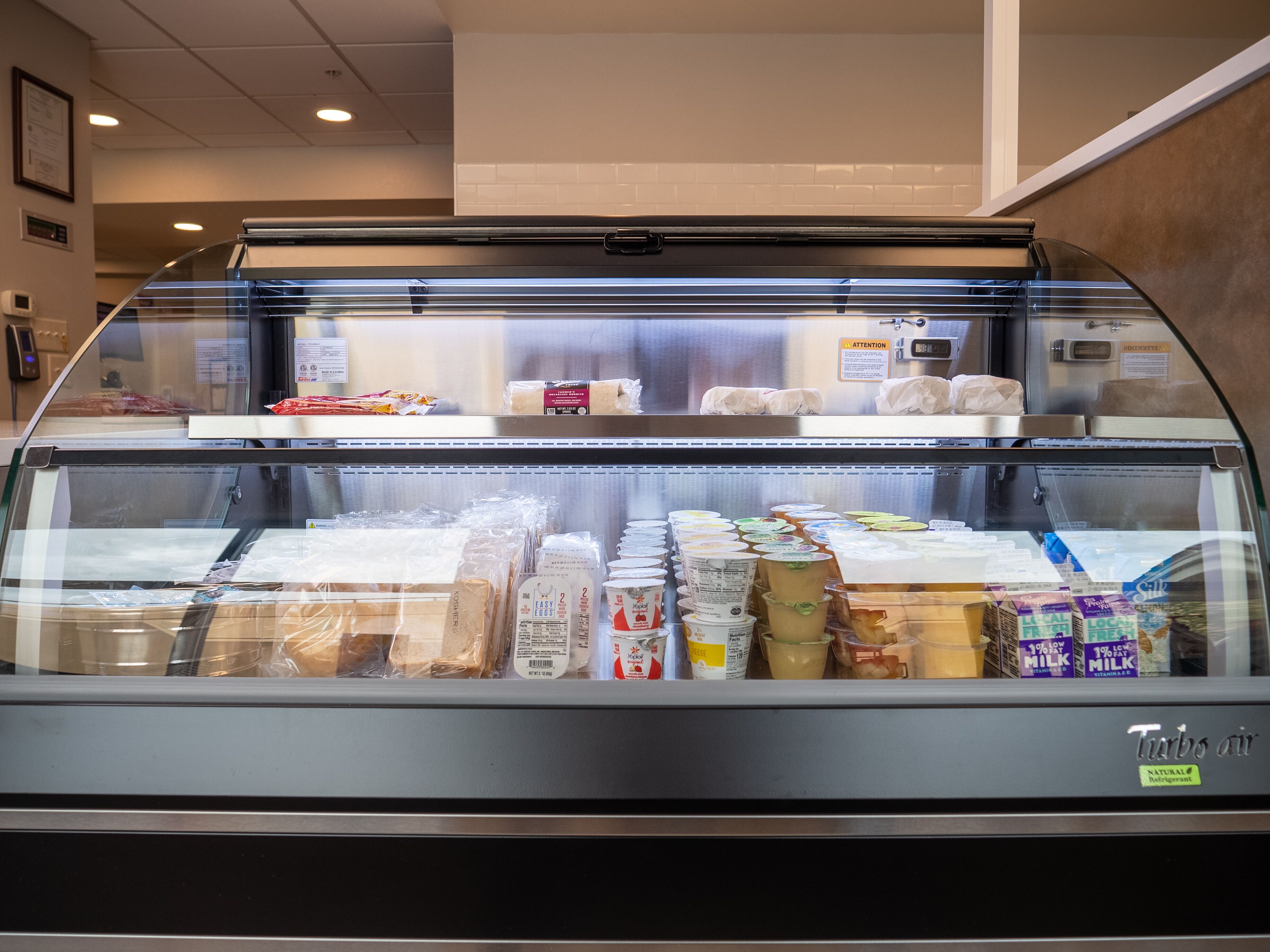 Mostrador refrigerado en una tienda con diversos productos lácteos y envasados.