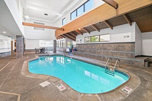 An indoor swimming pool with a clear water surface, surrounded by a stone deck and a tiled wall. - Beacon Pointe on Lake Superior (Duluth)
