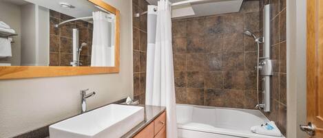 A modern bathroom with a white sink, vanity, and bathtub.