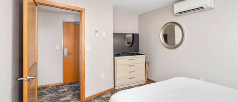 Een hotelkamer met een bed, een dressoir, een spiegel en een airconditioning.