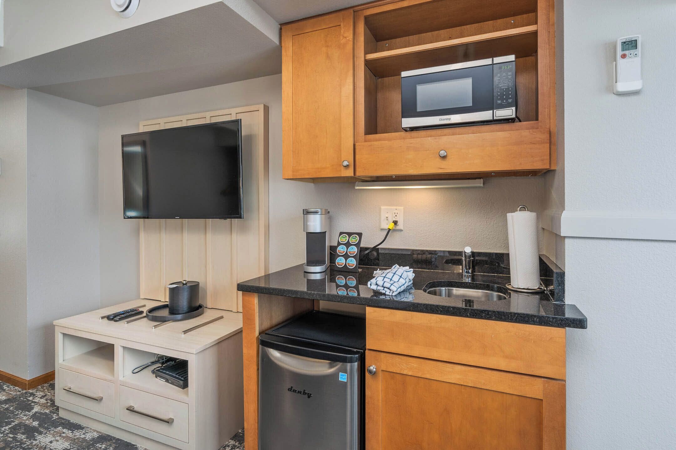 Una kitchenette compacta equipada con microondas, cafetera y un refrigerador pequeño.