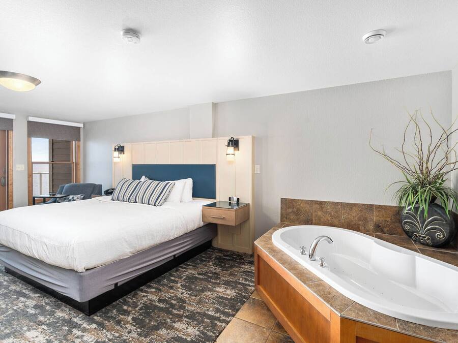 Een moderne hotelkamer met een groot bed, een inbouw bureau, een ligbad en uitzicht op zee.