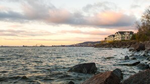 A waterfront property with a view of the sea and a distant city skyline.