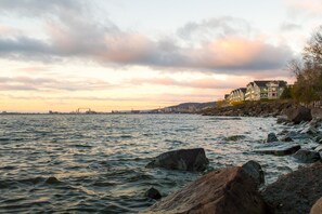 A waterfront property with a view of the sea and a distant city skyline.