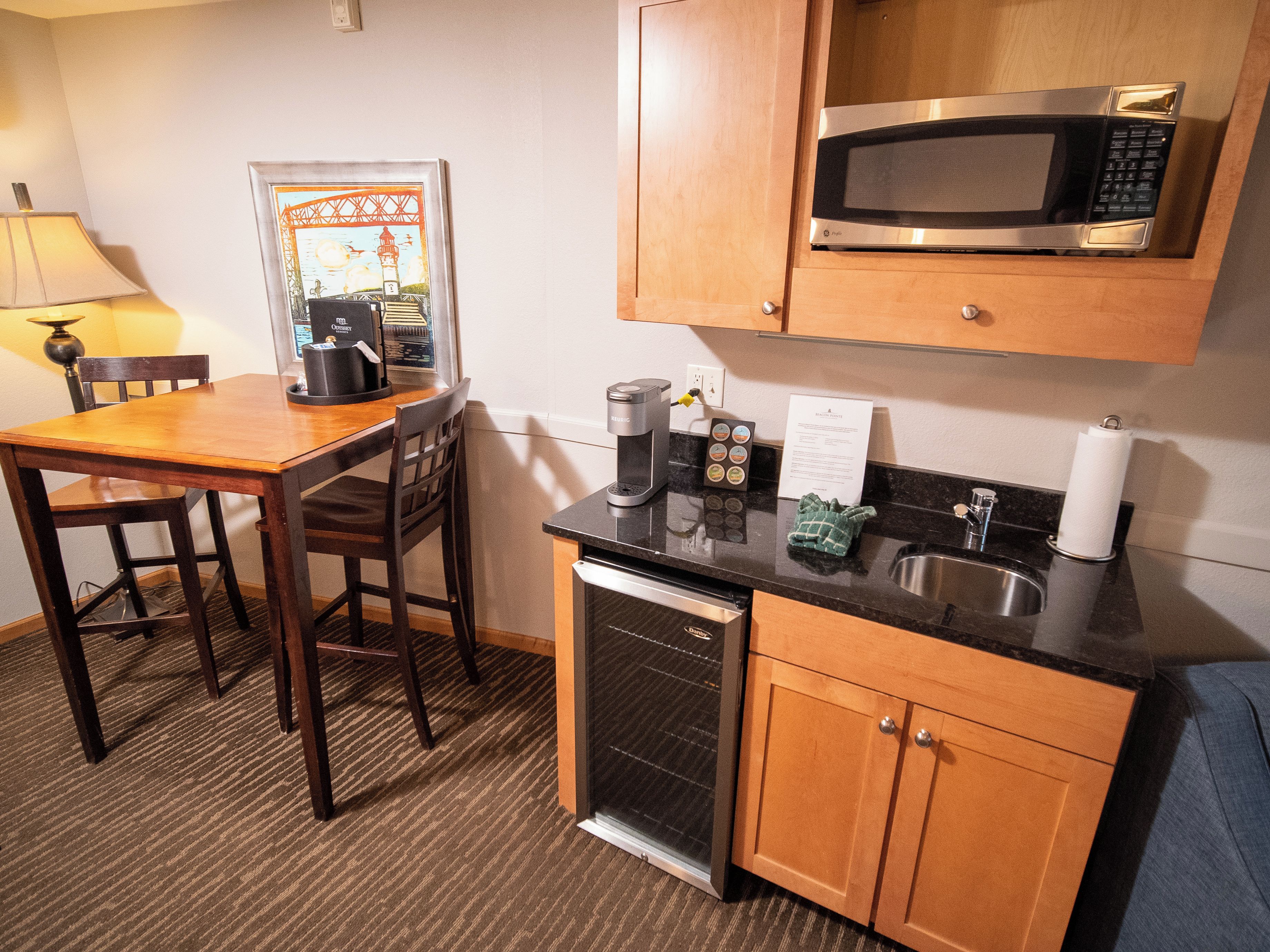 A compact hotel kitchen with a microwave, coffee maker, and a sink.