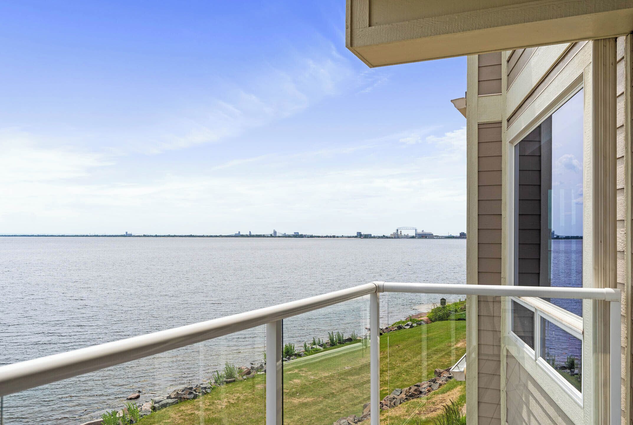 A balcony with a view of a large body of water and distant city skyline.