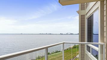 A balcony with a view of a large body of water and distant city skyline.