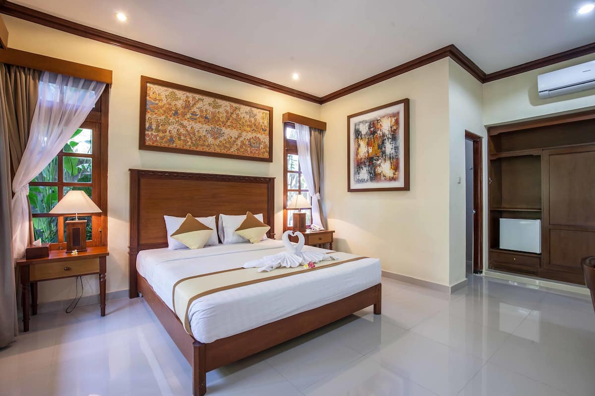 Une chambre d’hôtel avec un grand lit, une table de chevet, un bureau et une armoire.