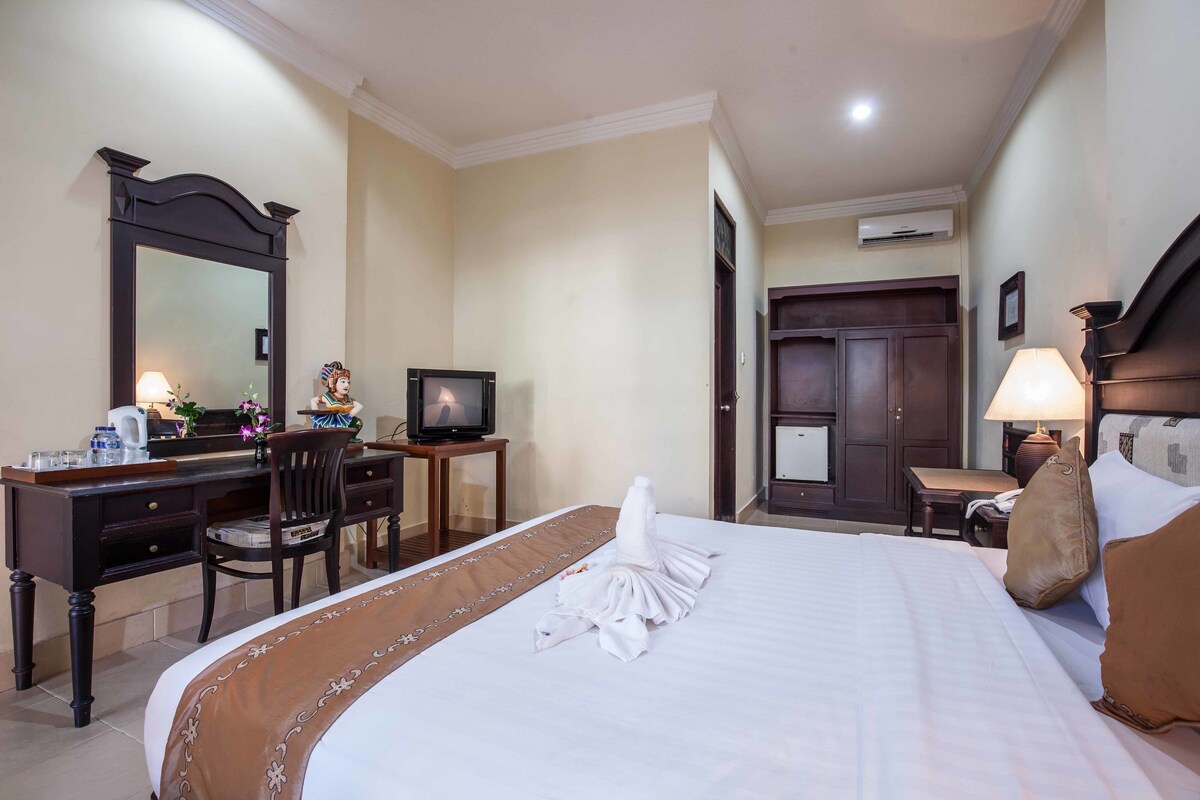 Ein Hotelzimmer mit Bett, Schreibtisch, Stuhl, Fernseher, Schreibtischlampe und Kleiderschrank.