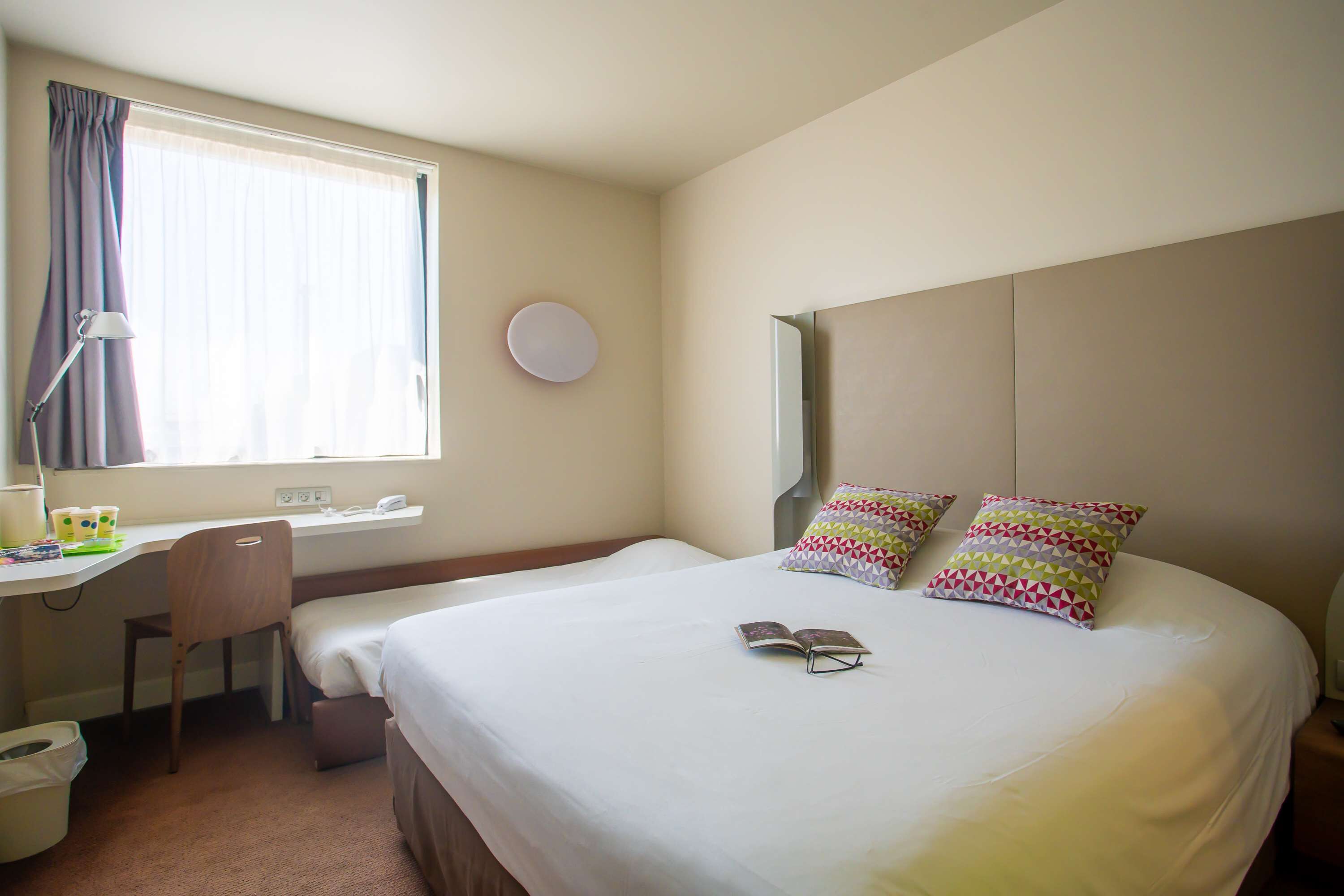 A hotel room with a bed, a desk, and a chair.