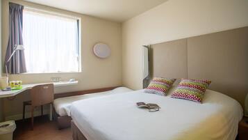 A hotel room with a bed, a desk, and a chair.