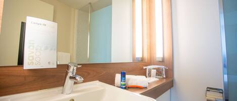 A bathroom with a white sink, a mirror, a towel, and a bottle of soap.