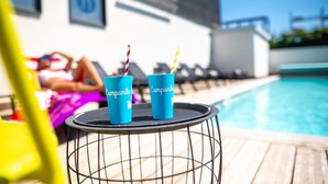 Un espace aménagé au bord de la piscine, avec deux gobelets bleus portant l’inscription « Companile » sur une petite table ronde.