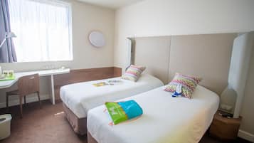A hotel room with two beds, a desk, a chair, and a window with curtains.