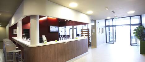 A modern reception area with a curved counter, bar stools, and a large window providing natural light.