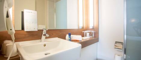 Un baño con un lavabo blanco, un espejo, un dispensador de toallas y un inodoro.