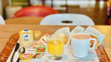 A breakfast tray with a cup of coffee, a glass of orange juice, cheese, butter, bread, and a newspaper.