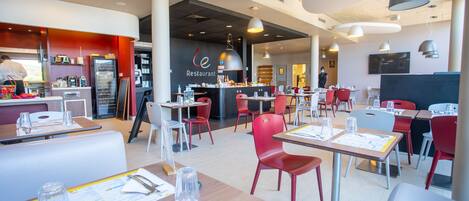 A modern restaurant interior with red and white seating, a central bar area, and overhead pendant lighting.
