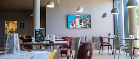 A modern dining area with tables, chairs, and pendant lighting.