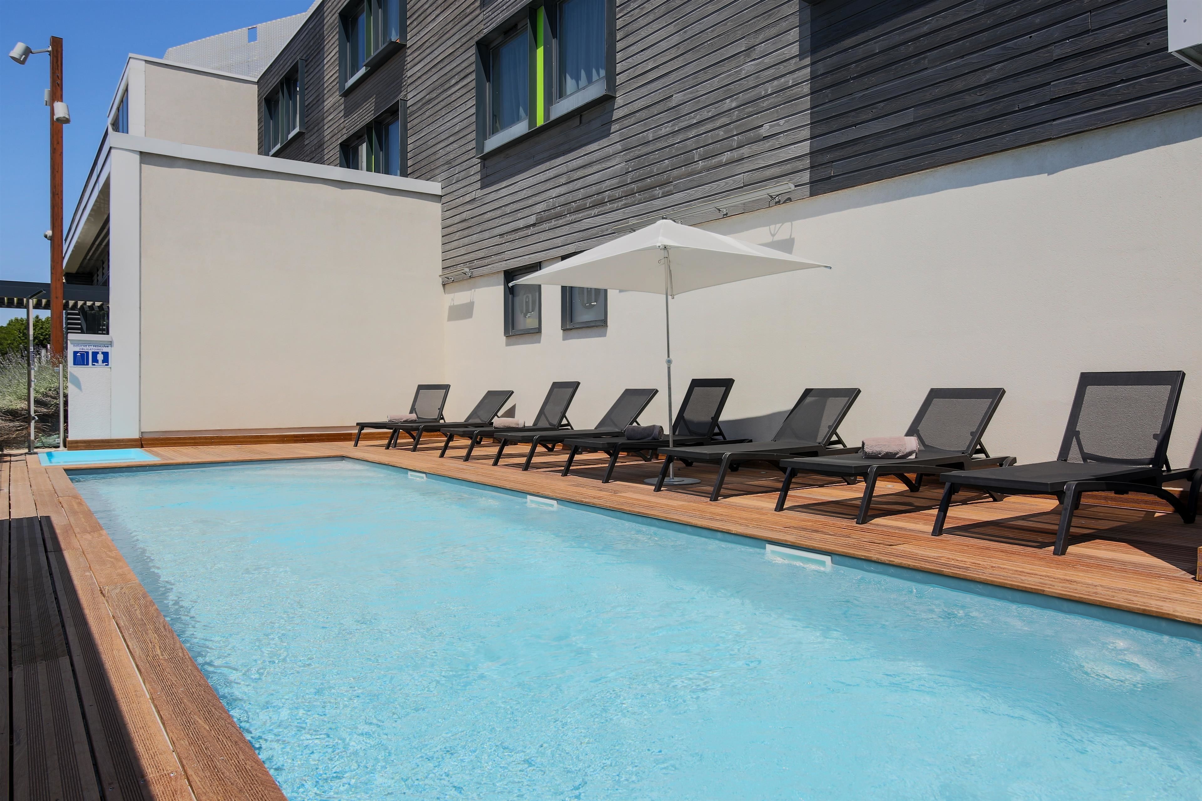 A swimming pool with lounge chairs and a white umbrella.