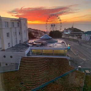 A modern building with a rooftop garden, a Ferris wheel in the background, and a sunset sky. - Sea Stone Hotel (Bournemouth)