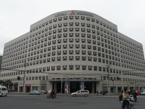 Un grand immeuble à plusieurs étages, doté d’une façade incurvée et d’une enseigne bien visible indiquant « JINJIANGINN ».