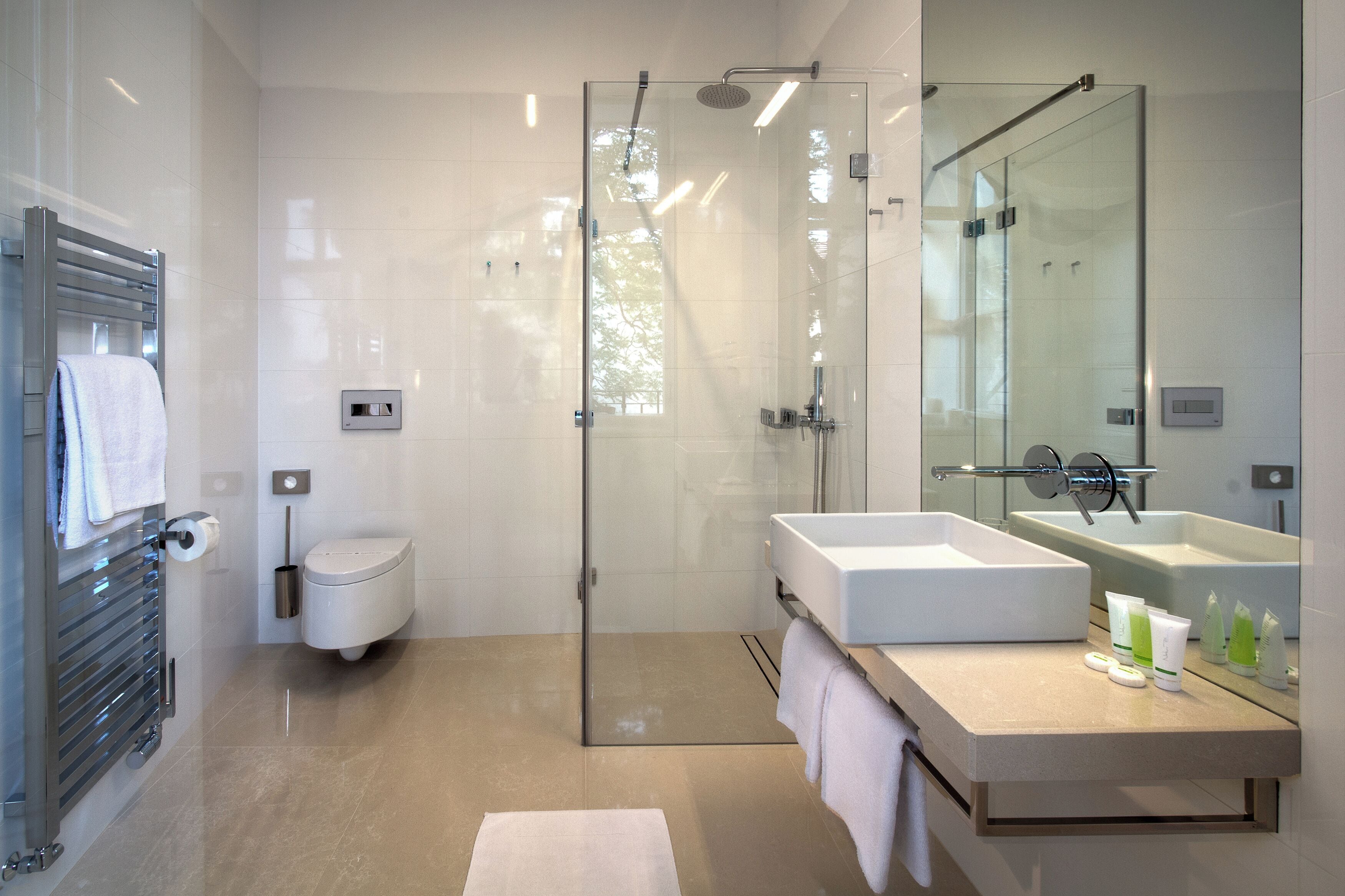 Un bagno moderno con doccia vetrata, WC bianco e mobile lavabo con ampio specchio.