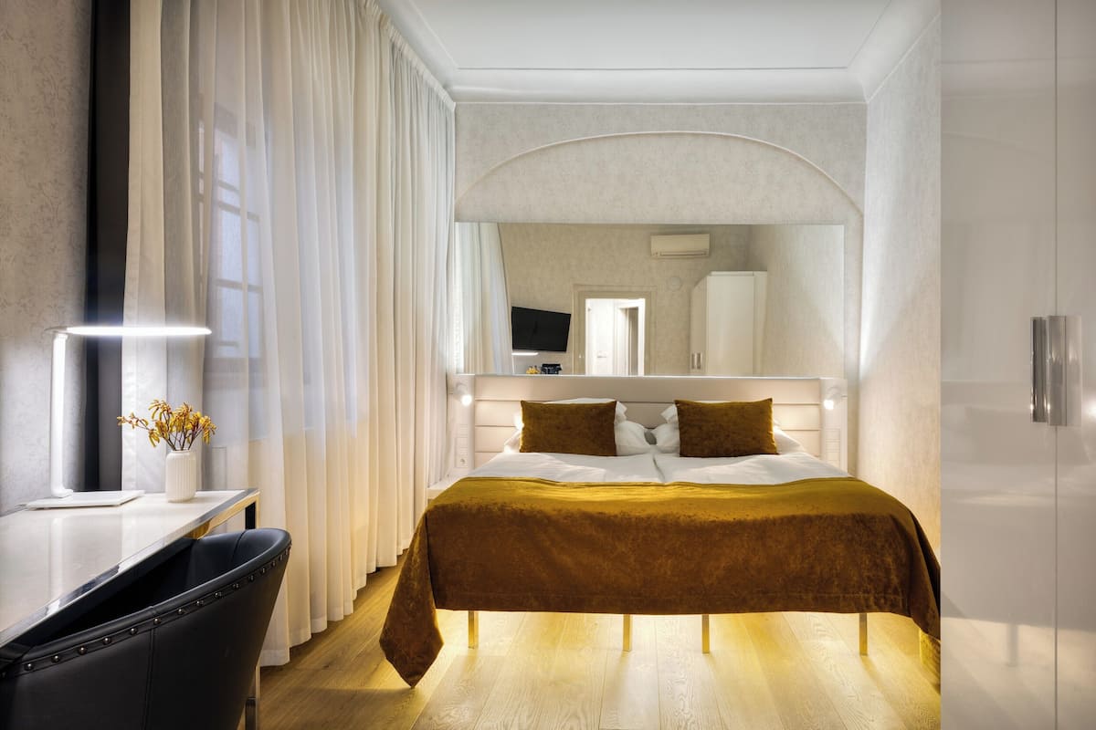Een moderne hotelkamer met een groot bed, een bureau met stoel, een televisie en een spiegel.