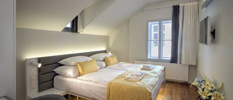 Un dormitorio moderno con cama, mesita de noche y ventana con cortinas.
