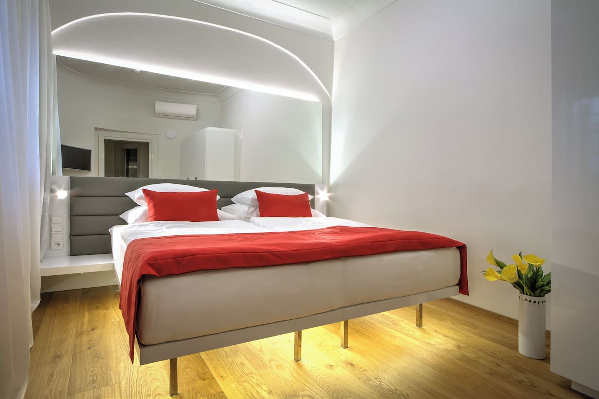 Een moderne slaapkamer met een bed, nachtkastjes, een spiegel en een plant in pot.