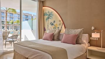 Habitación de hotel con una cama grande, una mesita de noche con lámpara, vista al área de la piscina y un mural en la pared.
