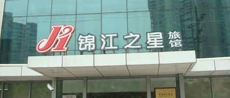 A hotel with a modern glass facade and a prominent red and white logo.
