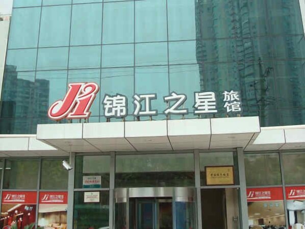 A hotel with a modern glass facade and a prominent red and white logo.
