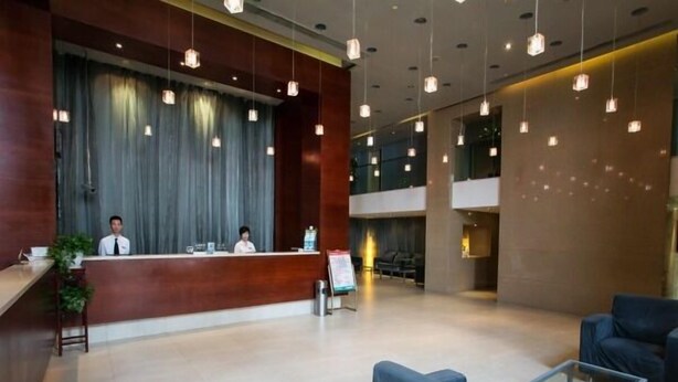 A modern hotel lobby with a reception desk, seating area, and a large window. - Jinjiang Inn Shanghai Lujiazui (Shanghai)