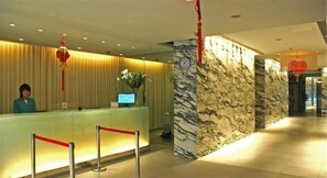 A hotel reception area with a marble wall, a reception desk, a clock, and a red decorative hanging. - Jinjiang Inn Shanghai Nanxiang (Shanghai)