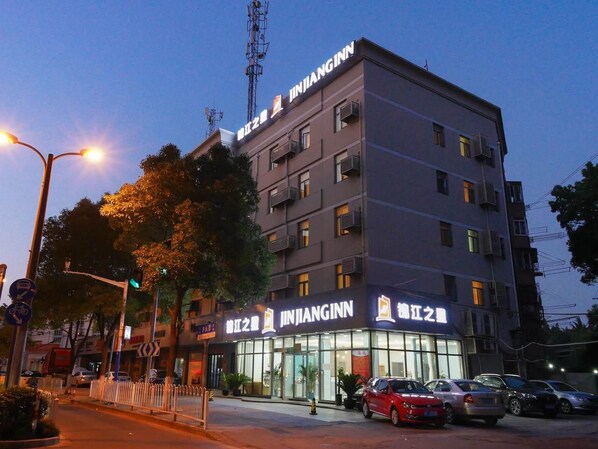 A multi-story hotel with a prominent signage, a gated entrance, and a parking area with several cars.