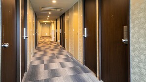 A hotel hallway with a checkered carpet, wooden doors, and a number 506 on the wall. - Green Hill Hotel Urban (Kobe)