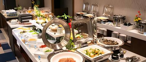 A buffet setup with various food items and serving utensils.