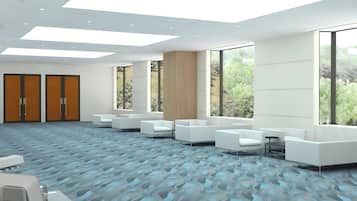 Una sala de conferencias moderna con mobiliario blanco, ventanas amplias y una alfombra estampada.
