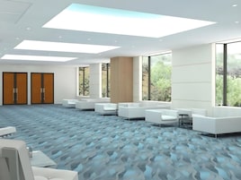 A modern conference room with white furniture, large windows, and a patterned carpet.