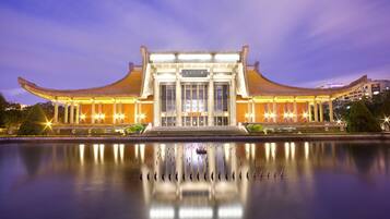 A traditional building with a symmetrical facade and a reflection in the water in front.