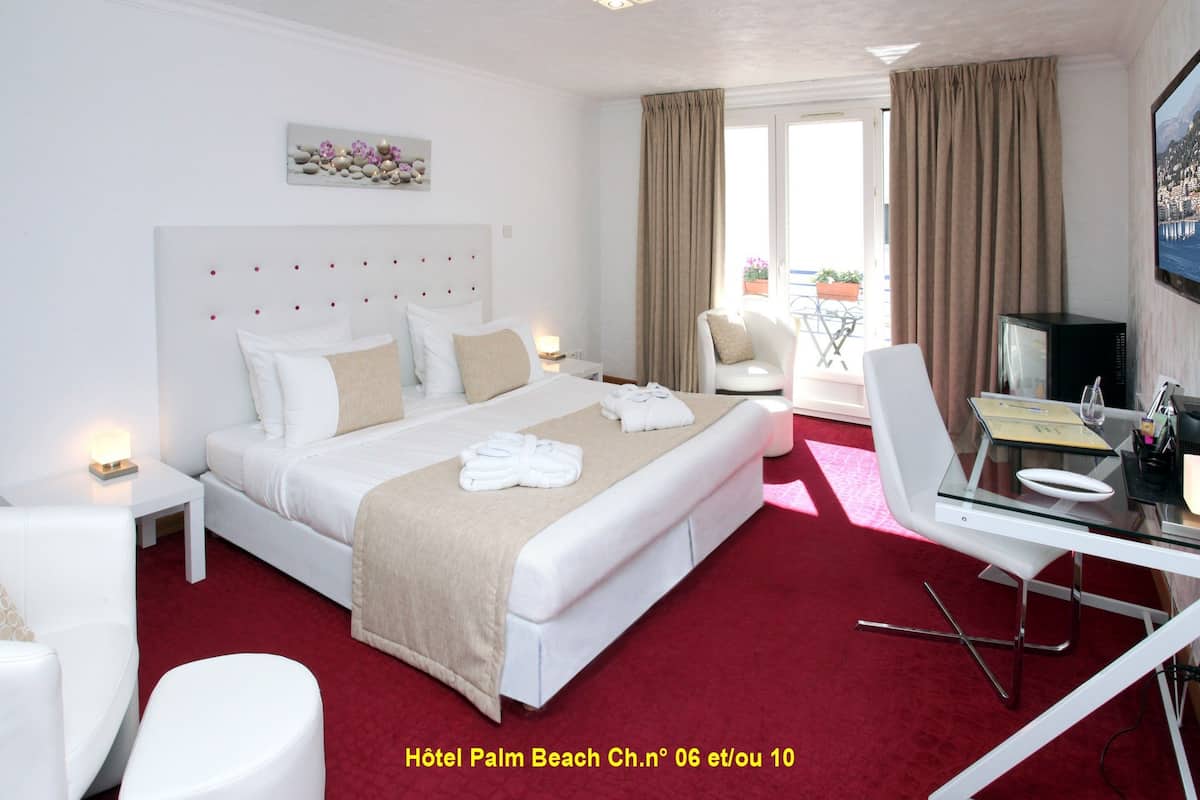 A hotel room with a large bed, a desk with a laptop, a chair, and a view of the outdoors.