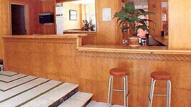Un espace bar avec des lambris en bois, un comptoir et deux tabourets.