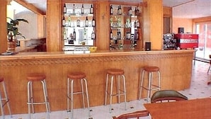 Un espace bar avec des tabourets et un comptoir où sont exposées différentes bouteilles.
