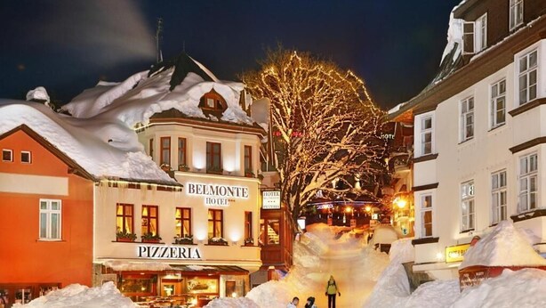 Een hotel met een pizzeria op de begane grond, omgeven door sneeuw.