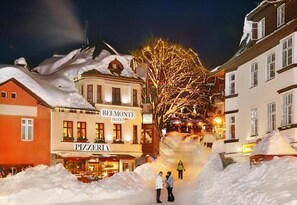 Un hôtel avec une pizzeria au rez-de-chaussée, entouré de neige.