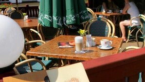 Een houten tafel met een menukaart met de tekst 'BELMONTE' en een groene parasol.