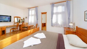 Een hotelkamer met een bed, een bureau, een stoel, een televisie en een spiegel.