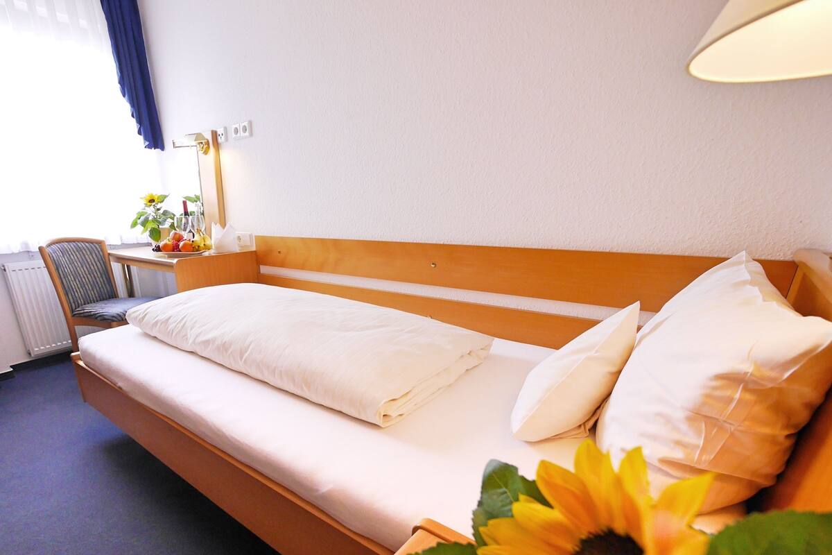 Een hotelkamer met een bed, een stoel, een bureau en een raam met gordijnen.